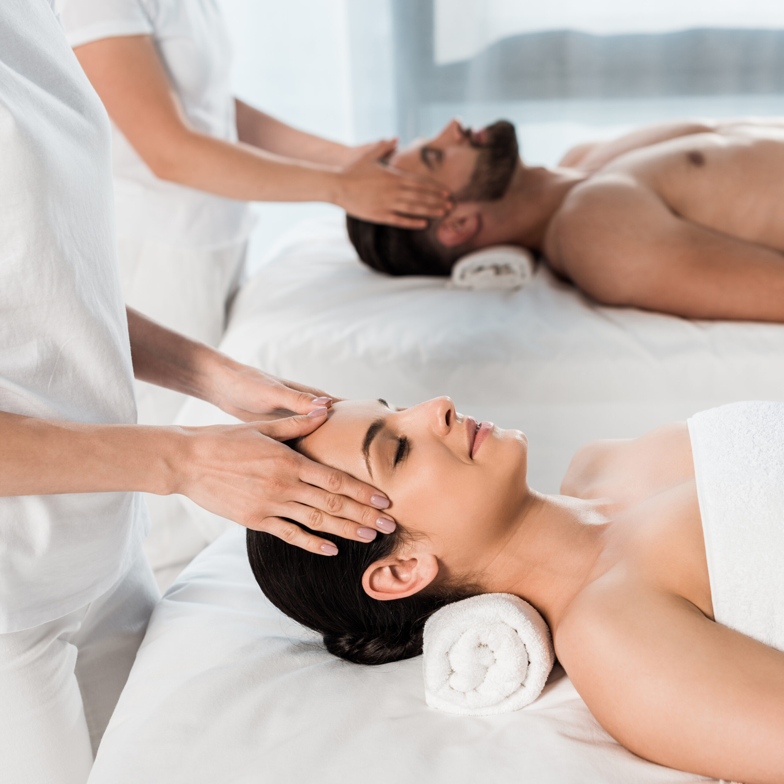 cropped view of masseurs doing massage to woman and man in spa center