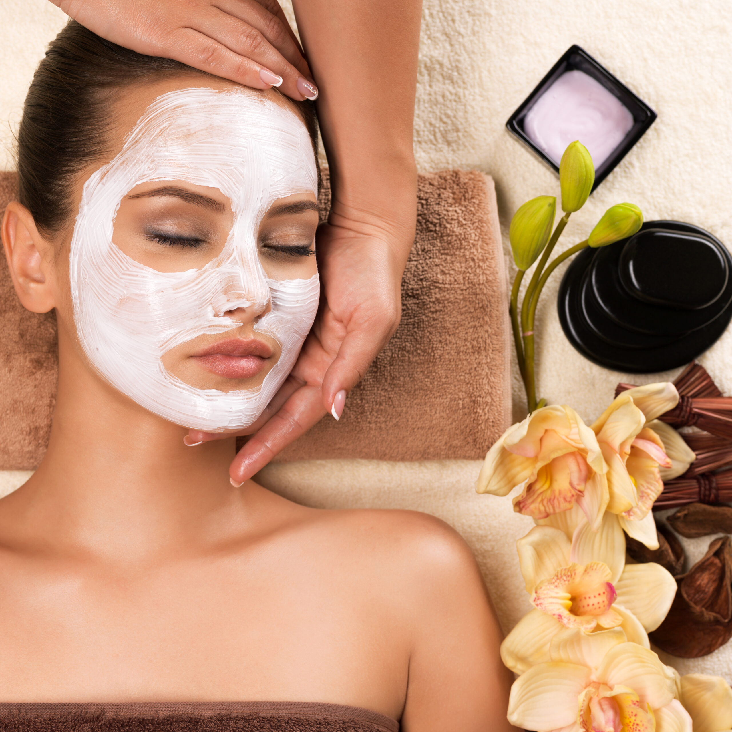 Beautiful woman with mask on her face having head massage in the spa salon.